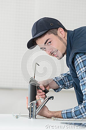 Young male plumber hand fixing tap sink in bathroom Stock Photo