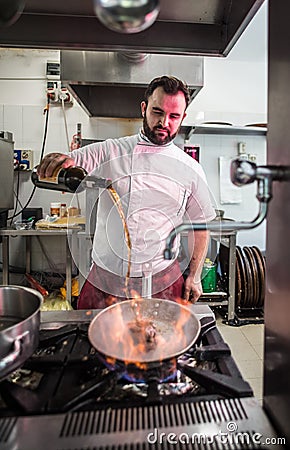 Chef preparing beef fillet steak in a frying pan with exploding flame Stock Photo