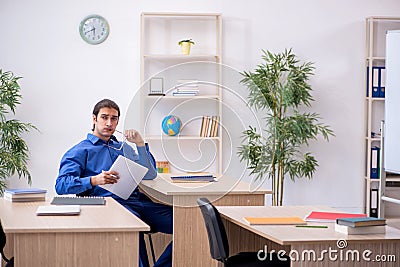 Young male teacher checking notes in the classroom Stock Photo