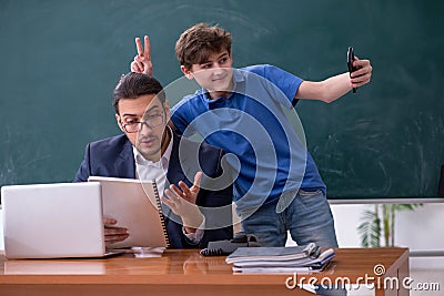 Young male teacher and schoolboy in the classroom Stock Photo