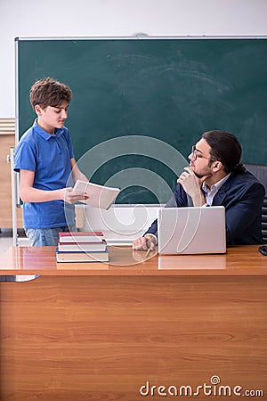 Young male teacher and schoolboy in the classroom Stock Photo