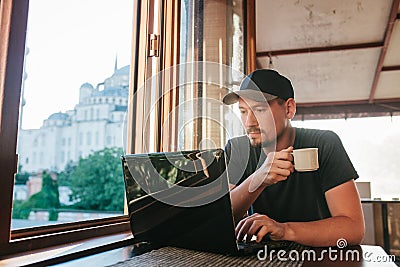 A young male tourist blogger freelancer working on a laptop in a cafe in Istanbul. A view from the window to the world Stock Photo