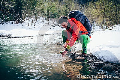 Young male tourist washes his face with river water in the mountains. Stock Photo