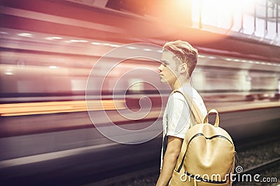 Young male traveler in station, with blurry train speeding Stock Photo