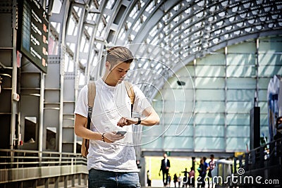 Young man at airport or station, looking at wrist watch Stock Photo