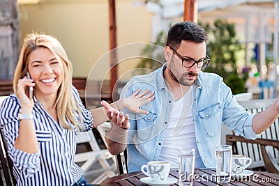 Young man is annoyed as his girlfriend spends too much time talking on the phone Stock Photo