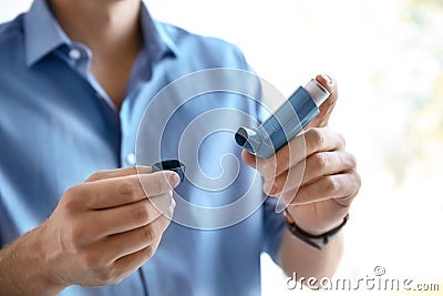 Young man with asthma inhaler indoors Stock Photo