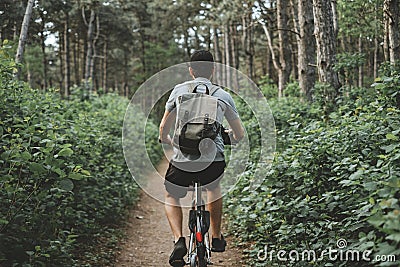 Young man with backpack cycling on a forest path, active lifestyle Stock Photo