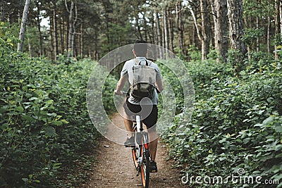 Young man with backpack cycling on a forest path, active lifestyle Stock Photo