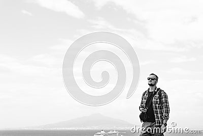 Young man with backpack standing with view on vulcano Vesuvius sea, ocean liner ship water craft. Travel and vacation concept. Stock Photo