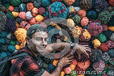 Young man with a backpack stands against a wall with multi-colored soft balls Stock Photo