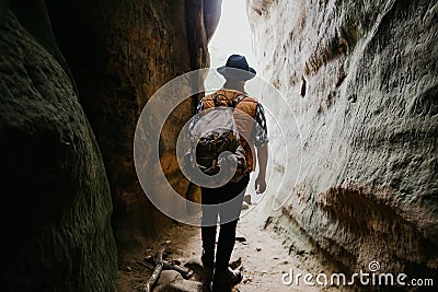 Young man with a backpack stands at a cave exit. Extreme summer vacation Stock Photo