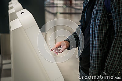 Young man with backpack touching interactive display using self service machine, doing self-check-in for flight or Stock Photo