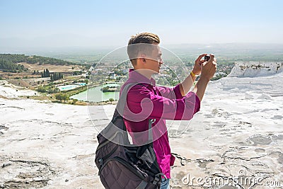 Young man with backpack, tourist, takes pictures with his mobile Stock Photo