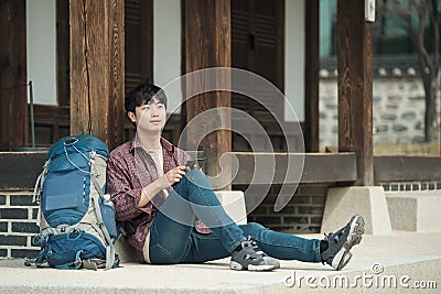 Young man backpacking in Korea. sitting in a Korean traditional house and using a tablet computer. Stock Photo