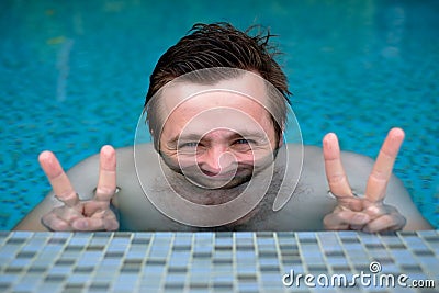 A young man is bathing in the pool and resting during the vacation. His face is distorted because of the water. Stock Photo