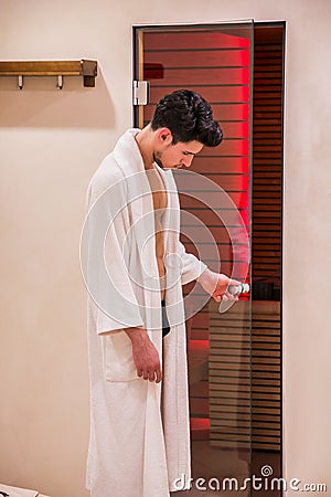 Young man in bathrobe entering or exiting sauna Stock Photo