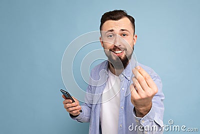 A young man with a beard on the background of a blue wall shows a gesture delicious close-up portrait Stock Photo