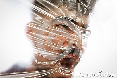 Young man with a beard suffocating with plastic around his head Stock Photo