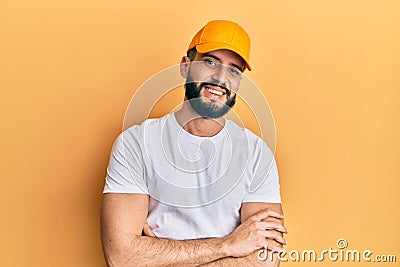 Young man with beard wearing yellow cap happy face smiling with crossed arms looking at the camera Stock Photo