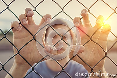 Young man behind wired fence. Immigration concept Stock Photo