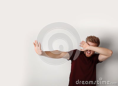 Young man being blinded and covering eyes with hand on background Stock Photo