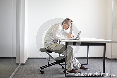 Young man is bent over his tablet.Bad sitting posture at work Stock Photo