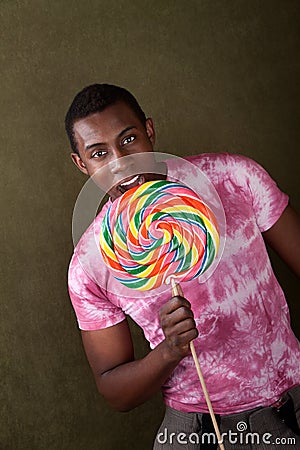 Young Man Bites Into a Giant Lollipop Stock Photo