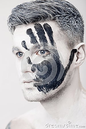 Young man with black hand print on white face. Closeup Portrait. Professional Fashion Makeup. fantasy art makeup Stock Photo