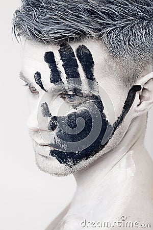 Young man with black hand print on white face. Closeup Portrait. Professional Fashion Makeup. fantasy art makeup Stock Photo