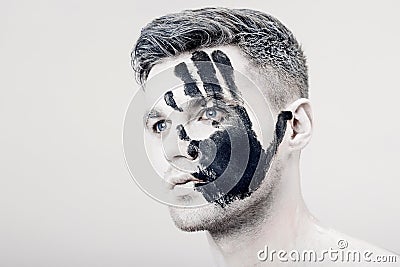 Young man with black hand print on white face. Closeup Portrait. Professional Fashion Makeup. fantasy art makeup Stock Photo