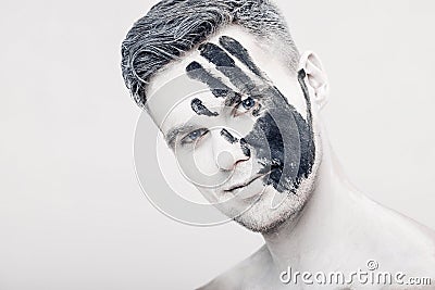 Young man with black hand print on white face. Closeup Portrait. Professional Fashion Makeup. fantasy art makeup Stock Photo