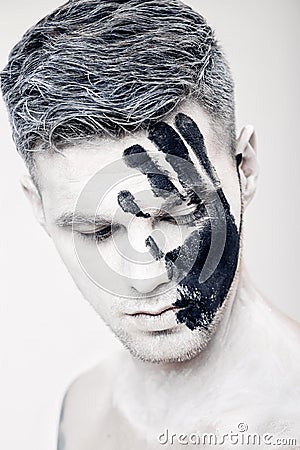 Young man with black hand print on white face. Closeup Portrait. Professional Fashion Makeup. fantasy art makeup Stock Photo