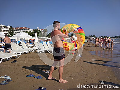 The young man blows his ring on the beach Editorial Stock Photo