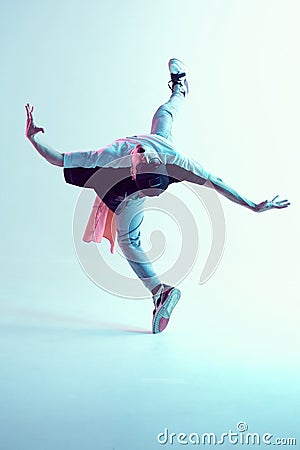 Young man breakdancer performs trick in jump dancing in studio in neon light. Break dance lessons. Dance school poster Stock Photo