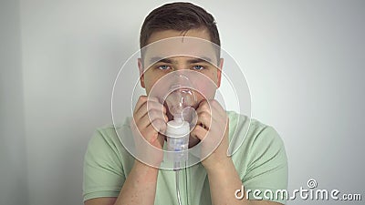 A young man breathes through an inhaler closeup. A man with an oxygen mask is being treated for a respiratory infection. Stock Photo