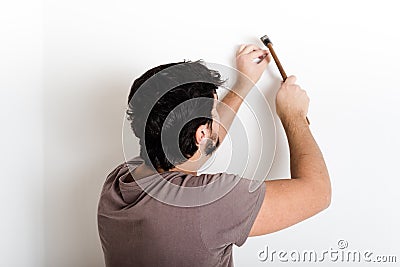 Young man bricolage hammering nail wall Stock Photo