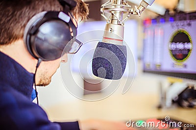 Radio moderator is sitting in a modern broadcasting studio and talking into the microphone Stock Photo