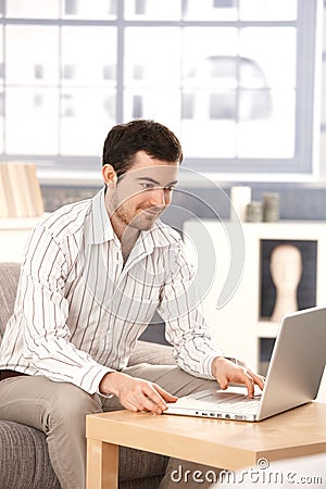 Young man browsing internet at home smiling Stock Photo