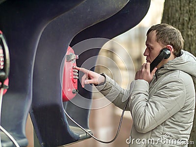 Serious young man calling by red street payphone Stock Photo