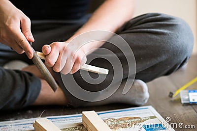 Young man, carpenter, handyman working with wood - polishing piece of wood with special devices Stock Photo