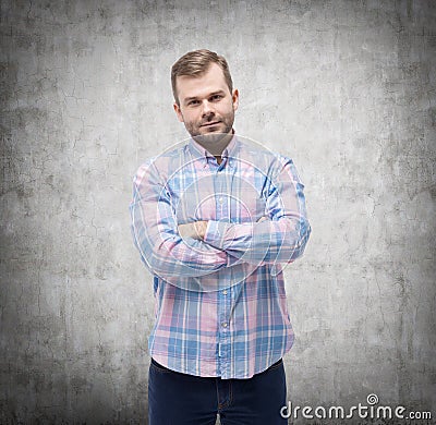 Young man in casual shirt with crossed hands. Concrete wall. Stock Photo