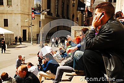 A young man chats on the phone while sitting at Wall Street Editorial Stock Photo