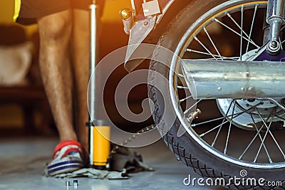 Young man check inflator pressure and inflates tire on motorcycle with bicycle floor pump. People checking air pressure and Stock Photo