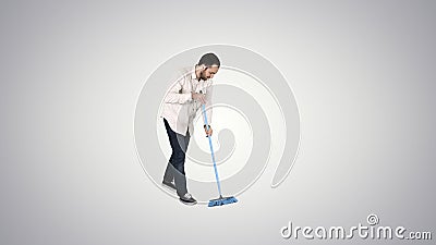 Young man cleaning floor with brush on gradient background. Stock Photo