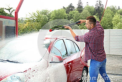 Young man cleaning vehicle with high pressure foam jet Stock Photo