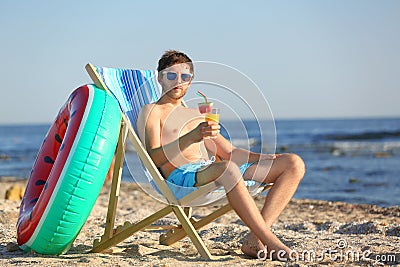 Young man with cocktail in beach chair Stock Photo