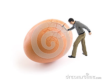 Young man cracking an egg using a hammer Stock Photo