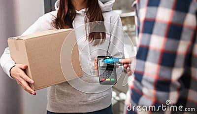 Young man with credit card using bank terminal for delivery payment at doorway Stock Photo