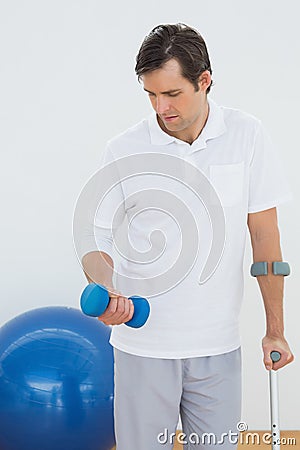 Young man with crutch and dumbbell Stock Photo